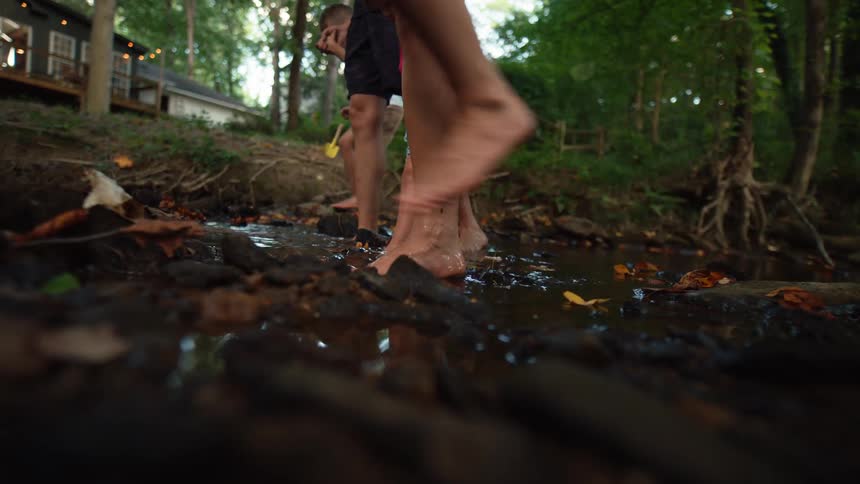 Family crossing a stream in a treelined area