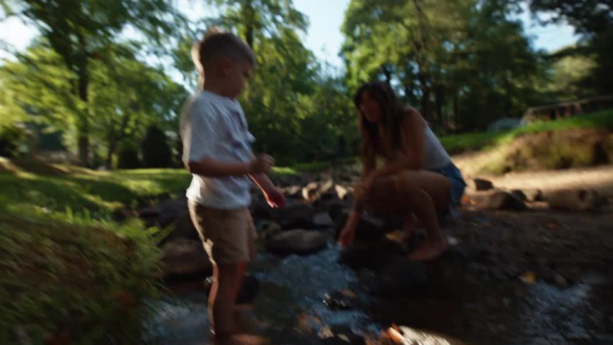 Woman throws water on a boy in a stream