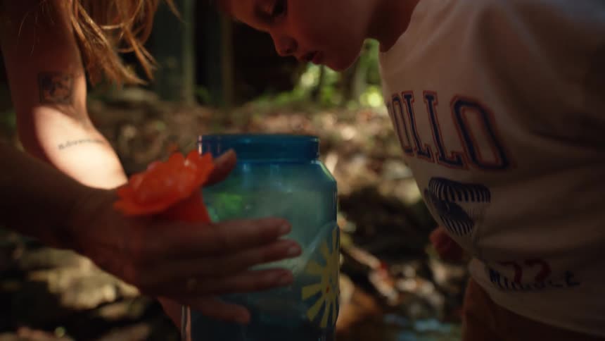 Little boy outdoors looking into a pot of water