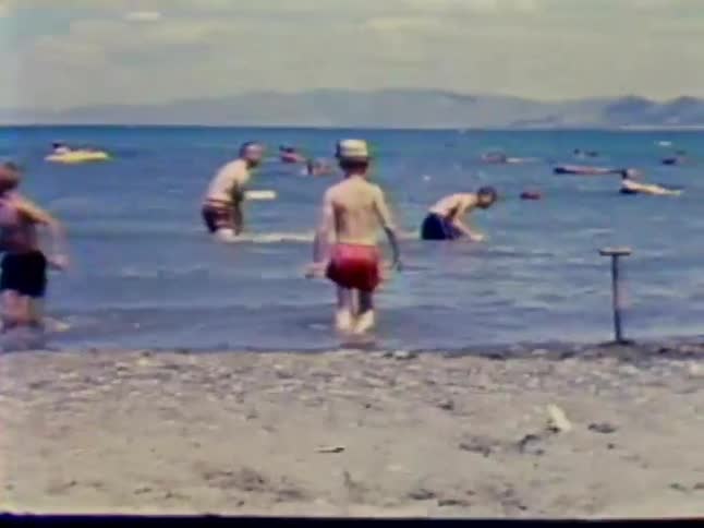 A man splashes a boy as children wade into the water
