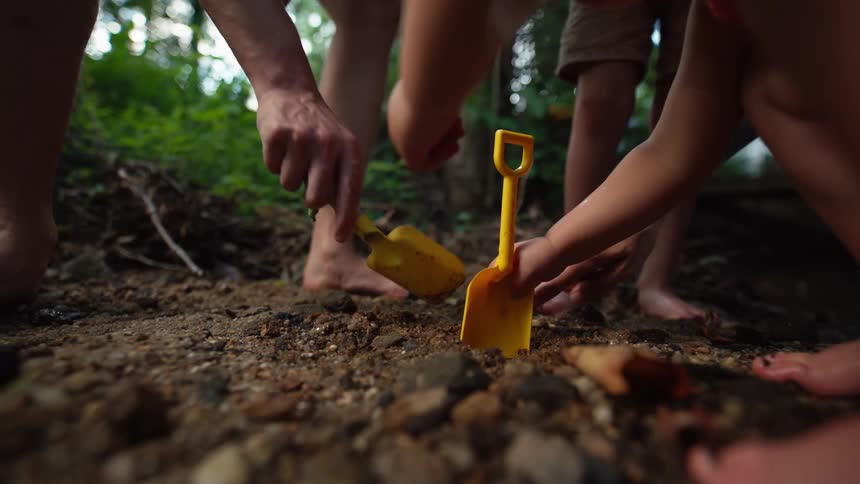 Children use yellow shovels to dig in the dirt