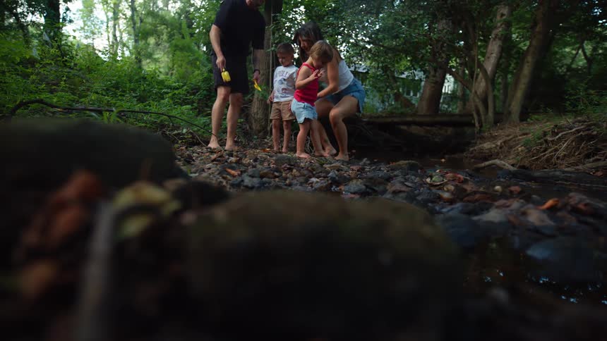 A family of foura father mother and two young kidsenjoys their time in the woods at midday