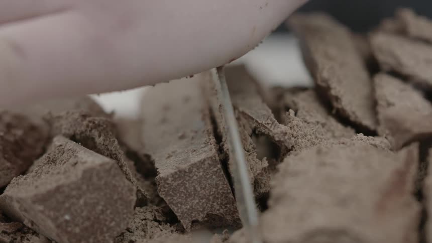 Chocolate pieces are being chopped with a knife