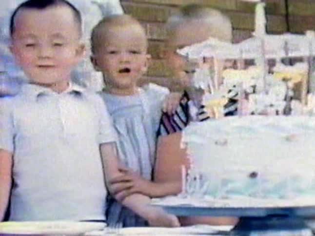 Children standing next to cake and smiling