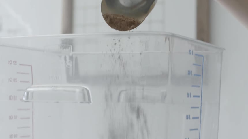 A scoop of cocoa is poured into a container