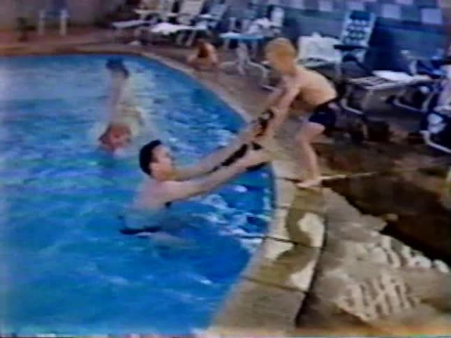 Man holds arms out as child is afraid to jump in the pool