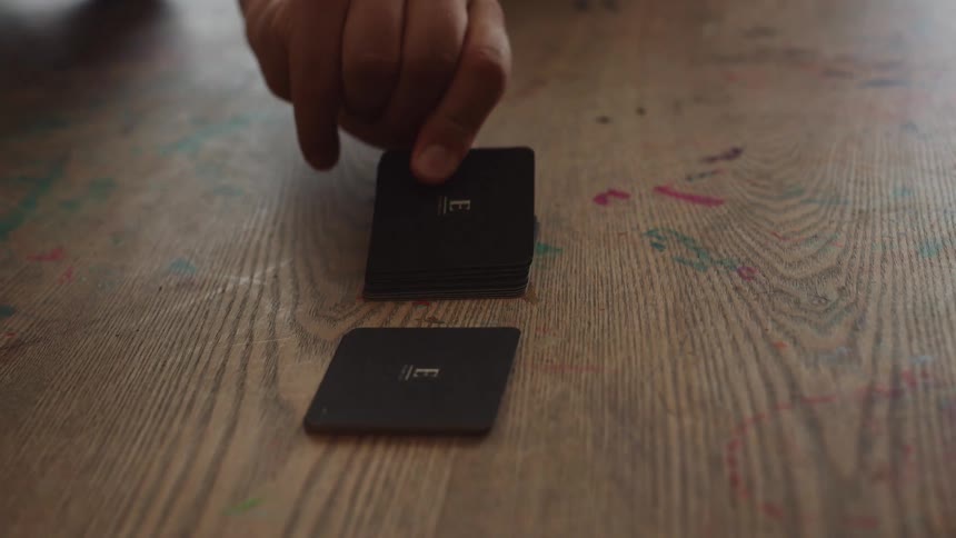 Person picking up a card from a game in the center of a wooden table