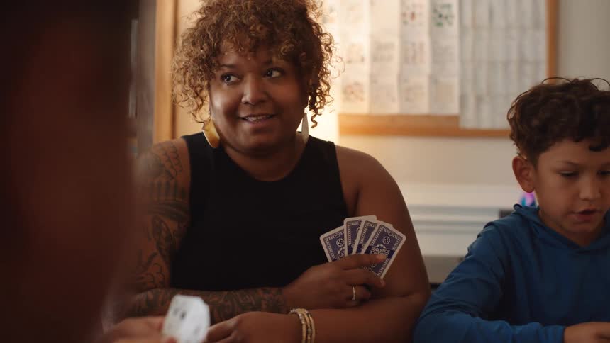 Four people sitting at a table having fun playing cards