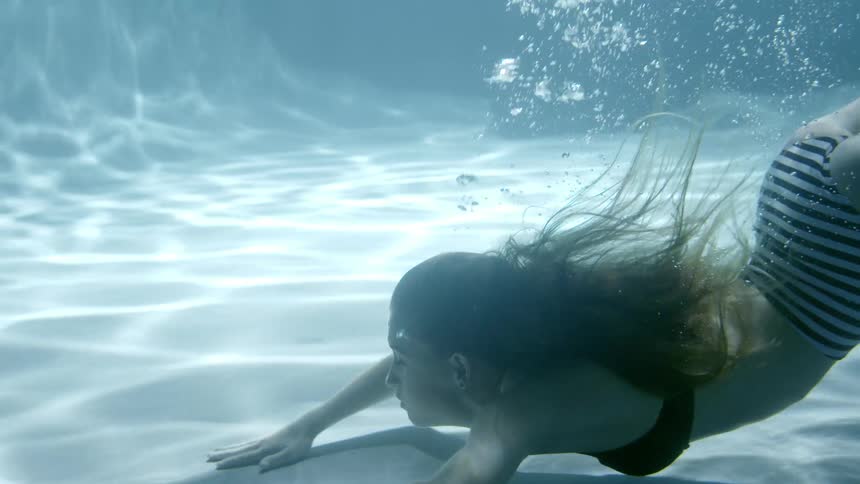A woman swims to the bottom of a pool then pushes back up