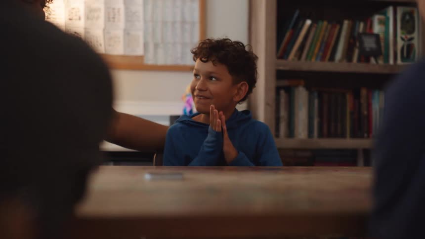 Boy focuses on reading a card while a woman smiles beside him