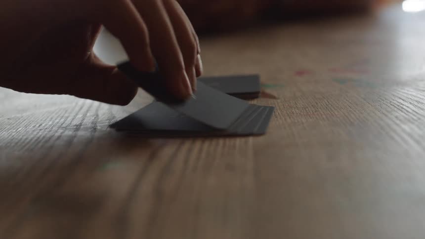 Hand moves cards on a wooden table