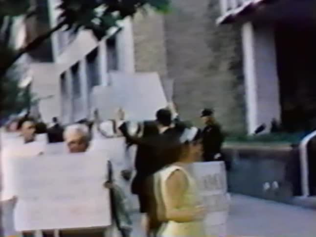 Men and women holding sings walk in a picket line