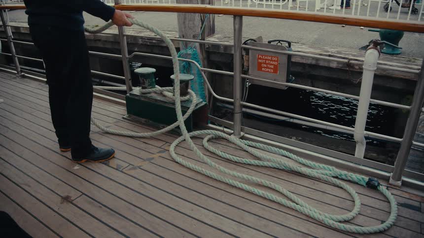 Person tying a rope to a boat support