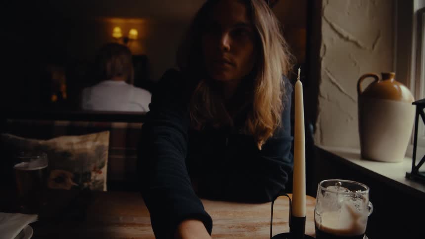 Close up of a young woman arranging cutlery while sitting at a table in a restaurant during daytime