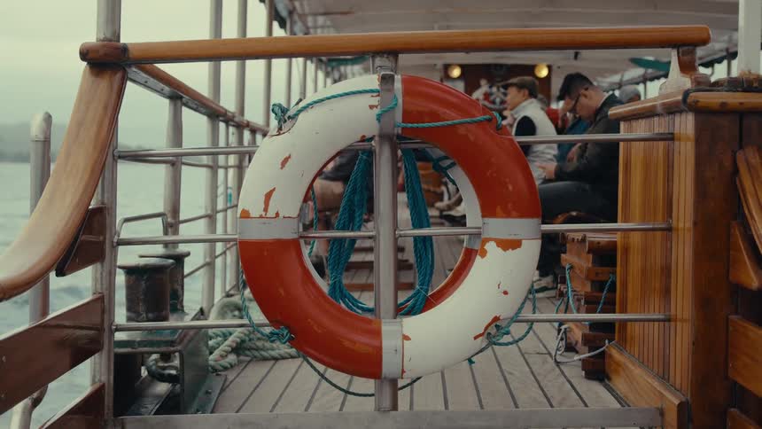 Orange and white lifebuoy attached to the railing of a boat