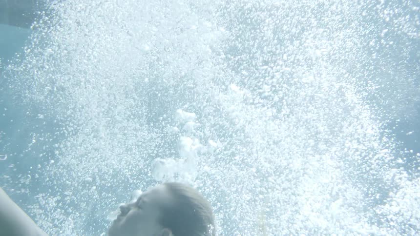 A woman falls under the water before diving up