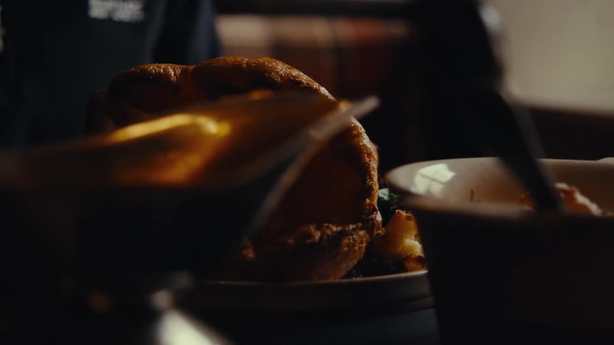 Close up of a person pouring syrup on their food before eating at a table indoors