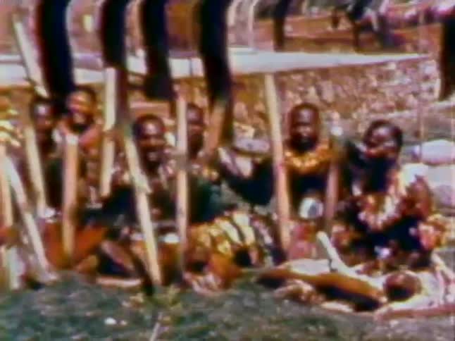 A group of tribesman hammer poles into the ground