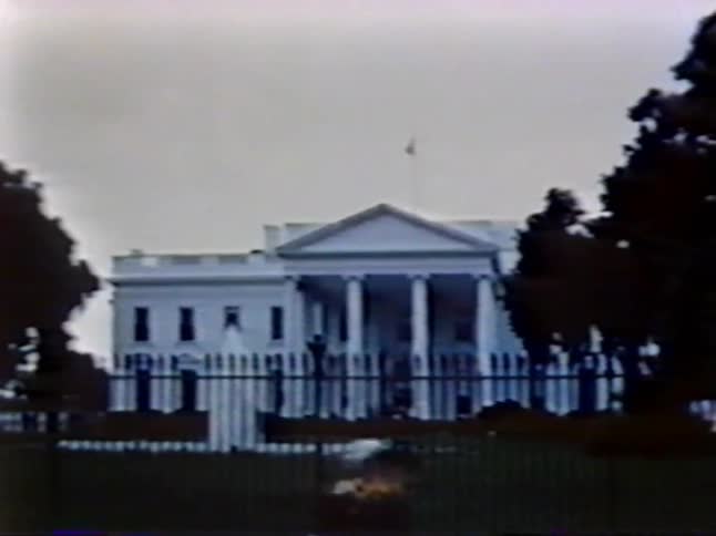 People walk past the fence of the white house