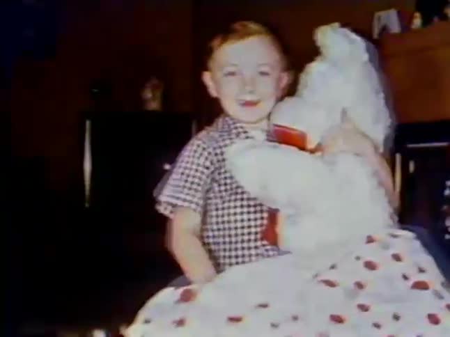 A boy opens up a present pulling out a large stuffed bear