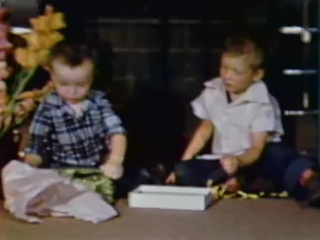 A woman opens a gift and the boys examine a bag