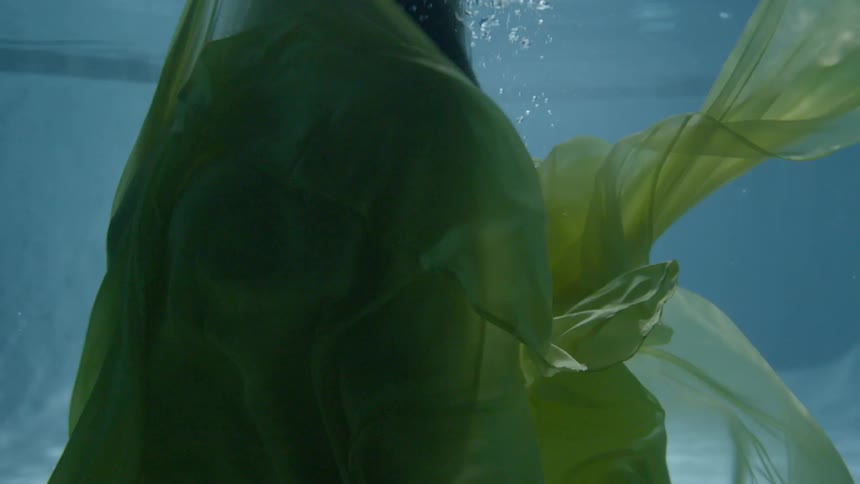 A woman swims underwater wearing a dress