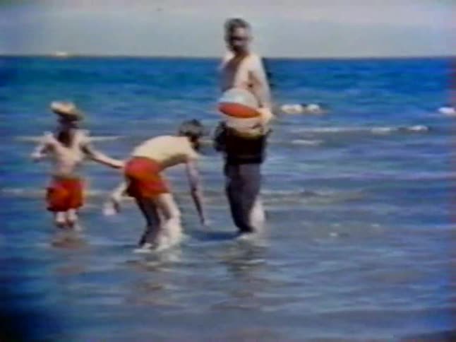 A family plays with a beach ball in the water