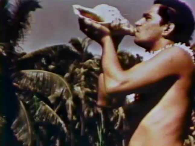 A man blows into a conch shell