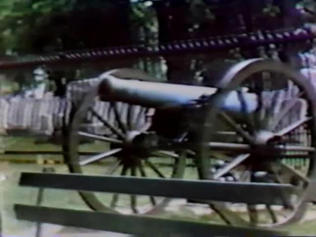 A canon is set in front of a cemetery