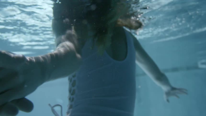 A man and woman hold hands underwater