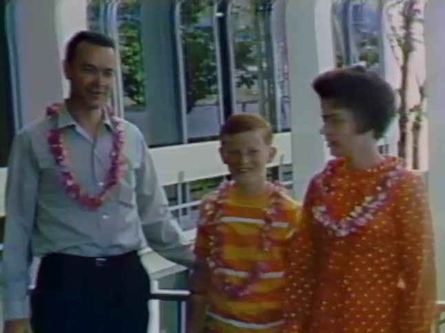 A man and woman pose with a child wearing leis