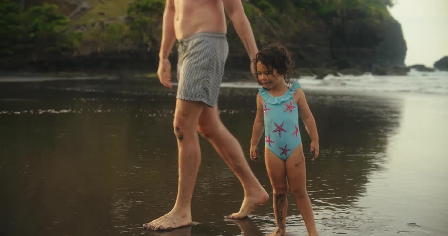 A child and an adult female and male play on a beach