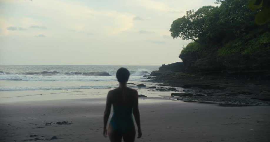 The woman walks towards the water on the beach