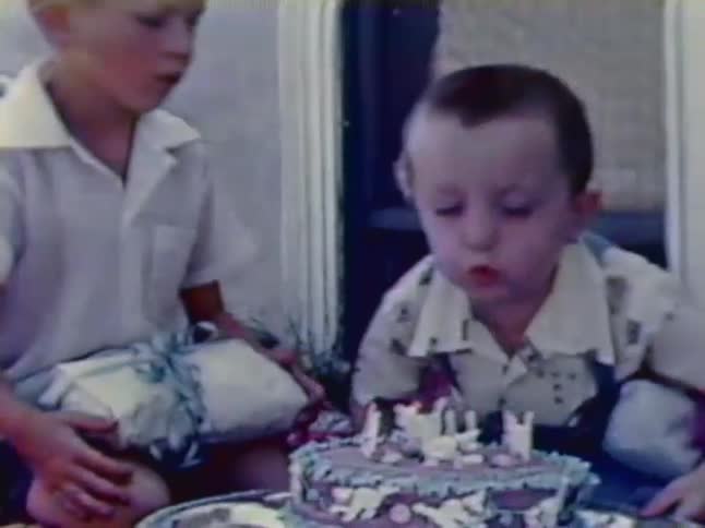 A boy blows out the candles on a birthday cake