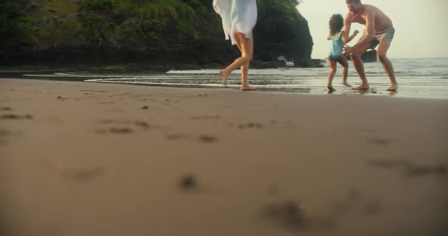A man a woman and a child play on a beach and walk into the water
