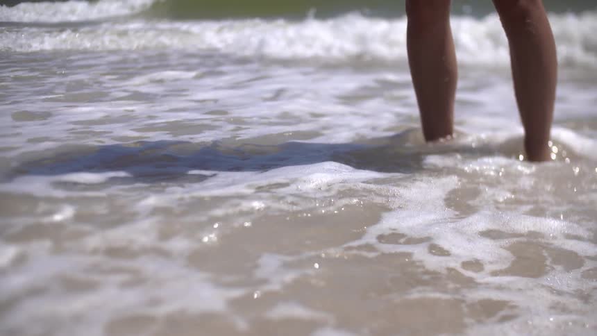 Person walking as waves hit their feet