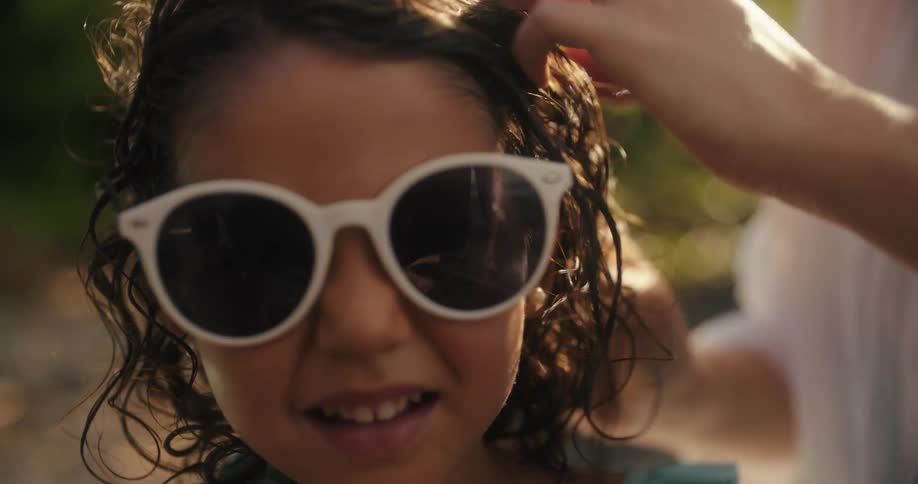 Person putting glasses on a curlyhaired child