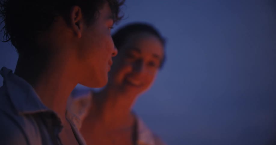 Young couple having a conversation in front of a bonfire at night