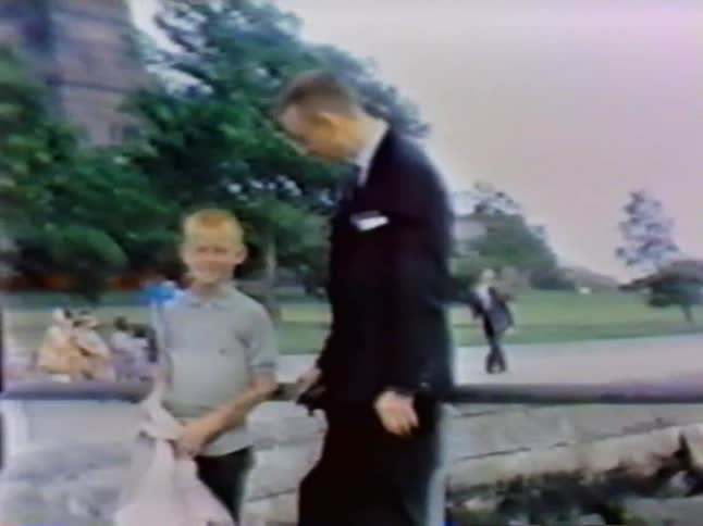 A young man stands next to a man in a suit