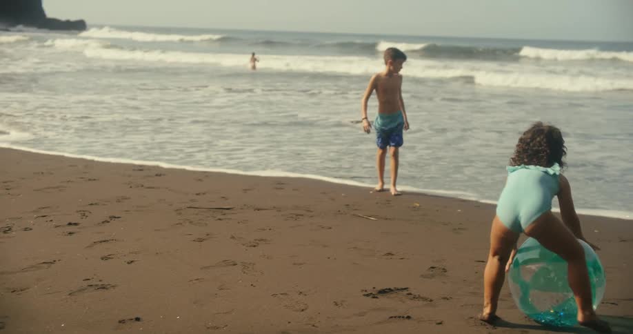 Kids play with a beach ball on the shoreline on a sunny day
