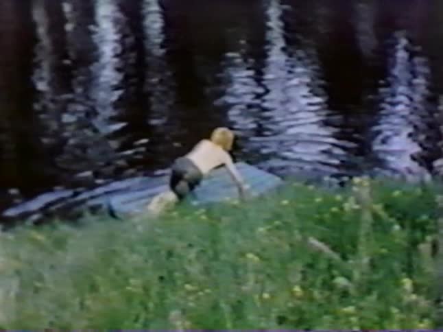 A boy jumps on a small raft in the water