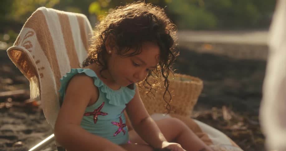 The child uses a small plastic shovel to dig in the sand