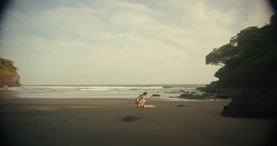 A woman lays down a towel to lay on at the beach