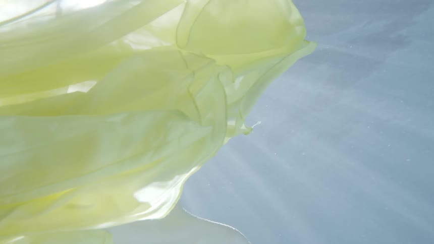 A person is swimming in the water wearing a yellow dress