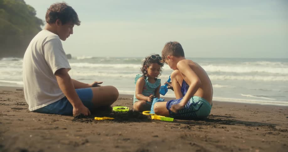 Children play in the sand on a beach next to the ocean