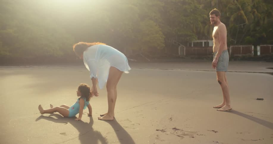 Parents watch their daughter play around the beach
