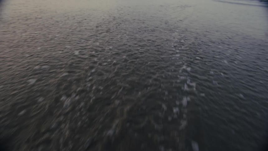 Low sweeping view of gentle ocean ripples at dusk with faint foam lines