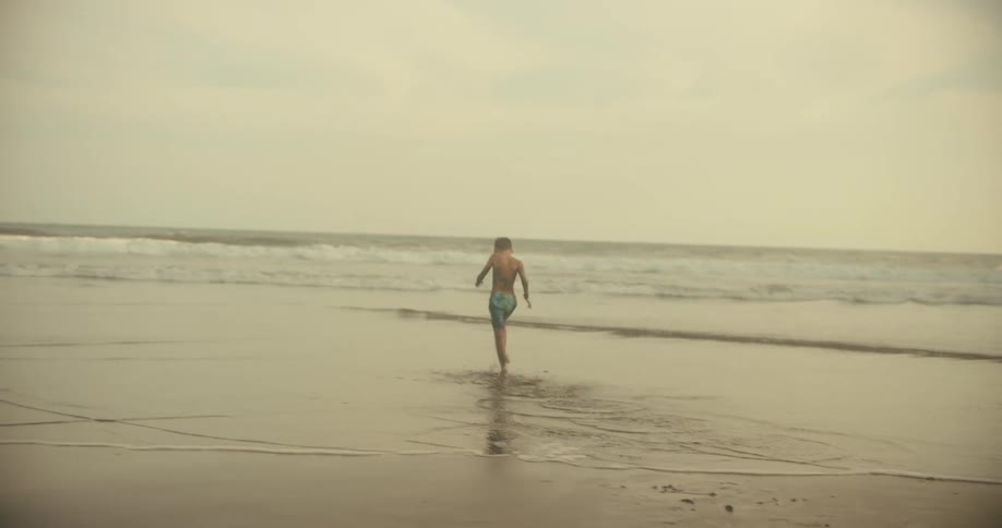 A boy playing with sand on the beach with two adult men