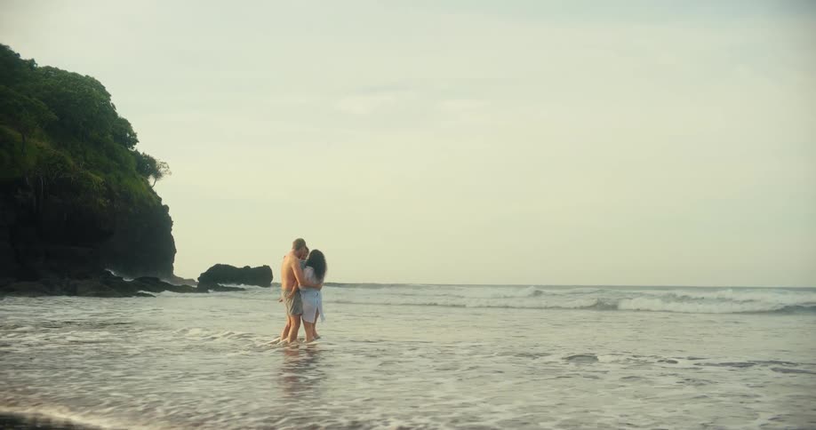 A mother and father hold their daughter while standing on the beach
