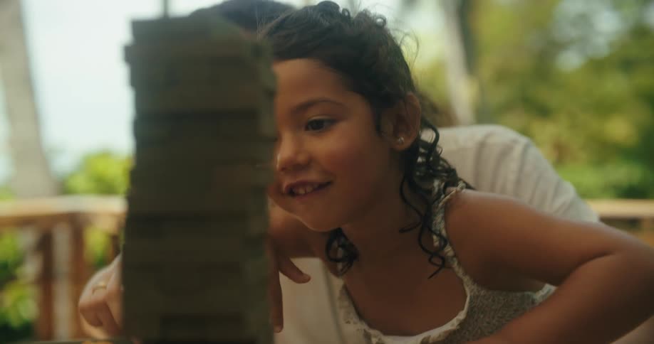 A mother holding her daughter in her arms playing with a block game on a table